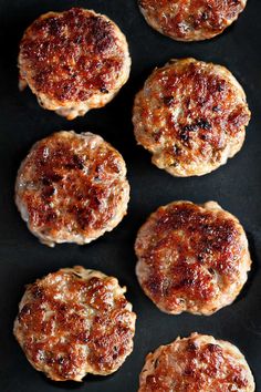 several hamburger patties are on a black surface and ready to be cooked in the oven