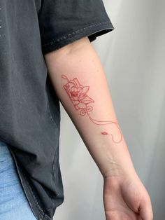 a person with a red ink tattoo on their arm holding onto a white object in his hand