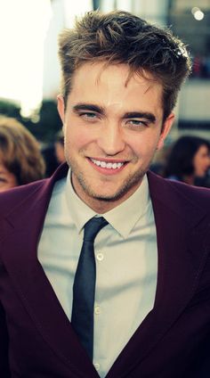 a man in a suit and tie smiling at the camera