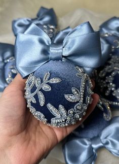 someone is holding a blue ornament with bows on it