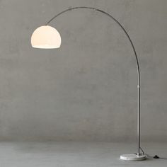 a floor lamp with a white shade on the top and an oval light fixture below it