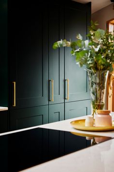 a kitchen with black cabinets and white counter tops, gold handles on the cabinet doors