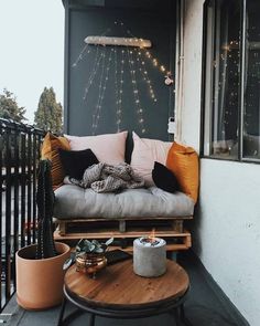 a couch sitting on top of a wooden table next to a window covered in string lights