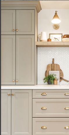 a kitchen with white cabinets and gold handles on the countertop, along with a cutting board