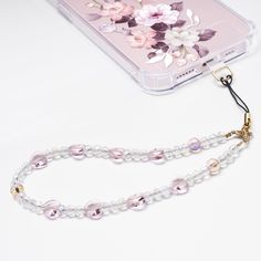 a phone case with flowers on it and a chain attached to the back of it