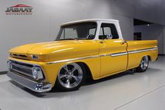 an old yellow pickup truck parked in a garage