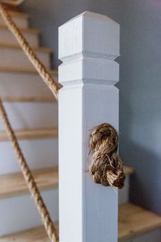 a rope is tied to the top of a white post next to some wooden stairs