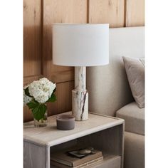 a white lamp sitting on top of a table next to a couch