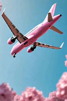 an airplane flying in the sky with pink flowers