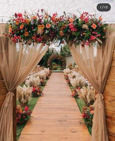 an outdoor ceremony with flowers and greenery on the aisle, decorated with sheer drapes