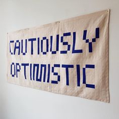 a white wall hanging with blue letters on it