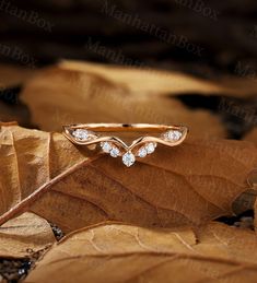 a gold ring with three diamonds sitting on top of leaves