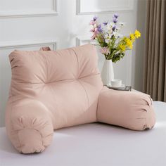 a pink couch sitting on top of a table next to a vase with flowers