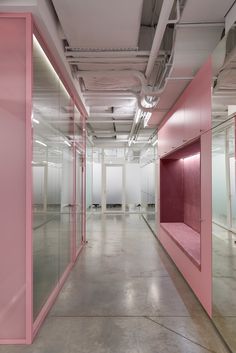 an empty room with pink walls and glass doors on the wall, in front of two rows of mirrors