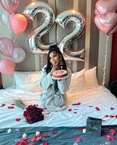 a woman sitting on top of a bed holding a cake in front of her face