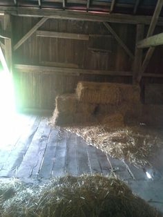 hay is piled up in an old barn with sunlight coming through the roof and onto the floor