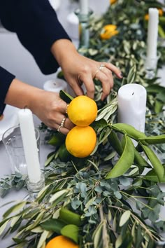 someone is decorating the table with lemons and greenery