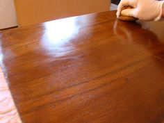 a person in white gloves cleaning a wooden table