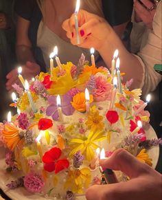 a person lighting candles on a cake with flowers