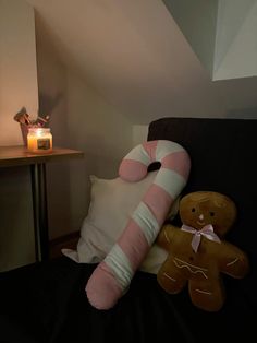 two teddy bears sitting on a couch next to a pillow with a pink and white stripe