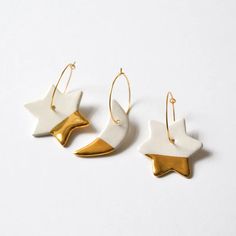 two white and gold earrings with stars on them