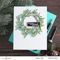 a handmade christmas card with a wreath on it and a pen next to it