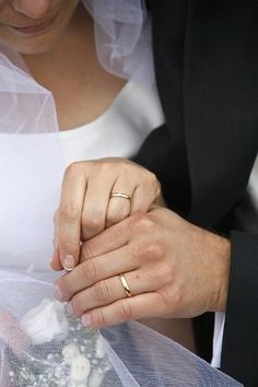 the bride and groom are holding hands with their wedding rings on top of each other