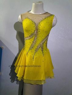 a yellow dress with silver sequins is on display in front of a white wall