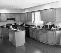 a large kitchen with wooden floors and white walls is pictured in this black and white photo