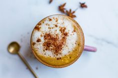 a cappuccino with cinnamon sprinkles on top and spoon next to it