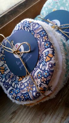 two round blue and white coasters with tags tied to them on a wooden surface