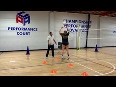 two people are playing volleyball in an indoor court with cones on the floor and one person is jumping up to hit the ball