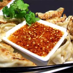 some food is sitting on a plate with chopsticks and sauce in the bowl