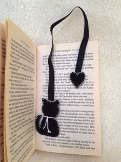 an open book with a black cat on it's cover and a tassel