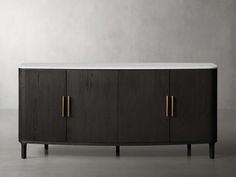 a black and white sideboard with two brass handles on the top, in front of a gray wall