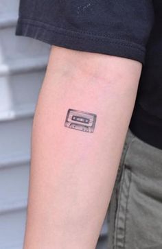 a small tattoo on the arm of a person with a tape recorder in front of them