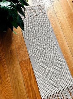 a white rug on the floor next to a potted plant and a wooden floor