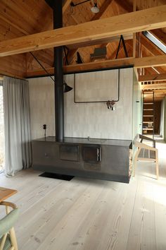 an empty living room with wood flooring and a large stove in the middle of it