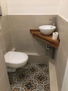 a white toilet sitting next to a sink in a bathroom under a wooden counter top