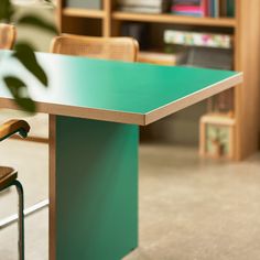 a green table with two chairs in front of it and bookshelves behind it