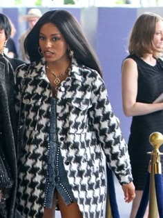 two women walking down the street in black and white coats, one wearing high heels