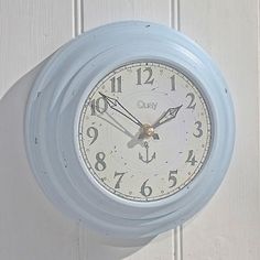 a blue clock hanging on the side of a white door