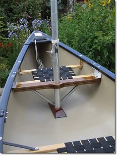 an empty boat is tied up to a pole on the ground in front of some bushes