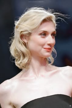 a woman in a strapless black dress posing for the camera with her hand on her hip