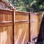 a wooden fence next to a tree in a yard