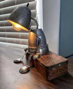 an old fashioned lamp sitting on top of a wooden table next to a box with spoons