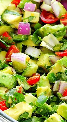 a salad with avocado, tomatoes, onions and cilantro in a bowl