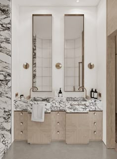 a bathroom with marble counter tops and two mirrors above the double sinks, along with gold faucets