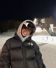 a woman standing on top of a snow covered slope wearing skis and a jacket