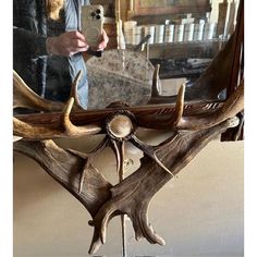 a man taking a photo of an antler's head in front of a mirror